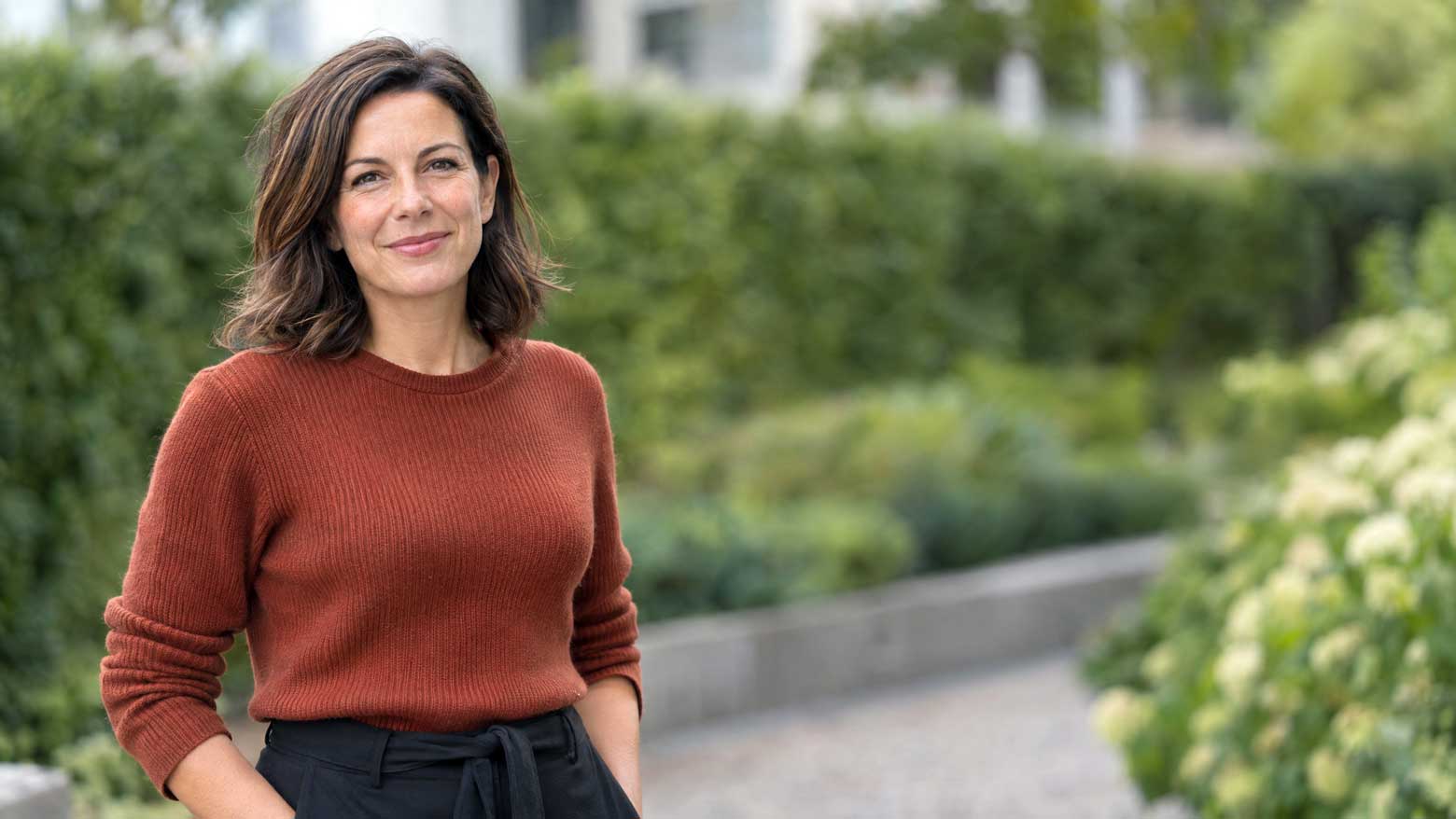 Ženska v rjavem puloverju, portret na prostem, čisto ozadje