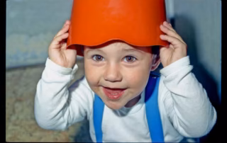 Nasmejan otrok z oranžnim loncem na glavi, začetki igre.